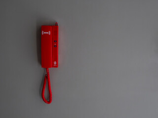 red emergency phone with an emergency notice sos icon on a handset placed on the wall