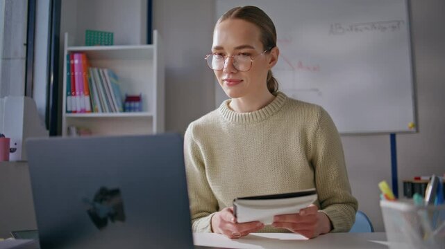 Smart woman conducting online lesson looking laptop screen at classroom closeup