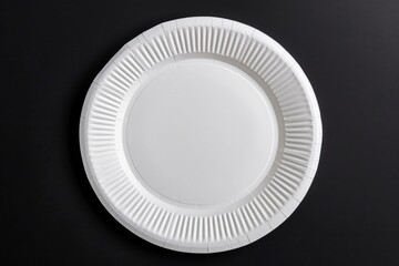 A simple white paper plate sitting on a black surface, great for use in presentations or product displays