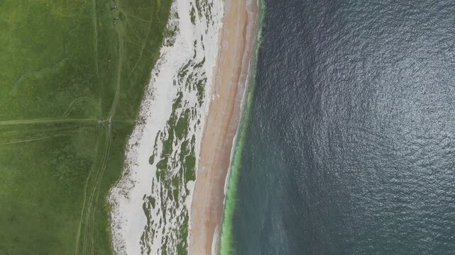 A high angle drone shot of ocean coastline with blue waters and white cliffs.