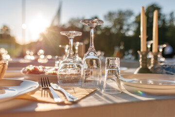 empty wine glasses on banquet served table in open air in rays of setting sun