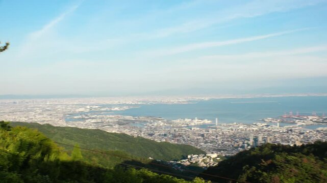 KOBE, HYOGO, JAPAN - JUNE 2024 : Aerial high angle panoramic view around Kobe city, Kobe port, Osaka city and Osaka bay in daytime. View from top of Rokkosan (Mt. Rokko).