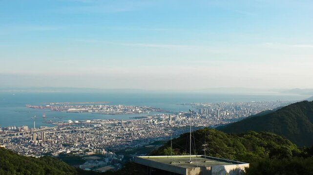 KOBE, HYOGO, JAPAN - JUNE 2024 : Aerial high angle panoramic view around Kobe city, Kobe port, Osaka city and Osaka bay in daytime. View from top of Rokkosan (Mt. Rokko).