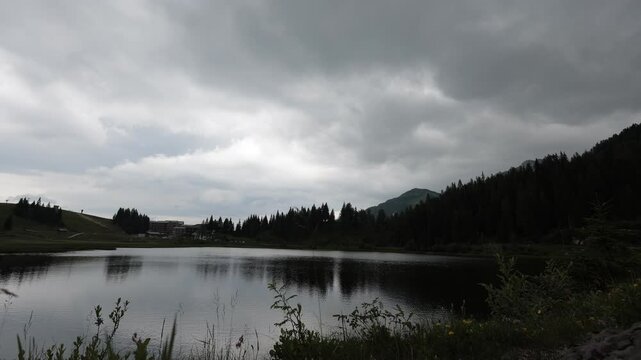 Timelapse 4k video of Pramollo lake with a hotel next to it at a high alpine pass of Nassfeld. Green scenery in the alps