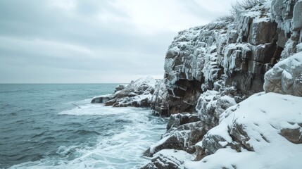 Snowy coastal cliffs with icy formations along a foggy seascape. Concept of winter landscape, nature, cold weather, seashore tranquility