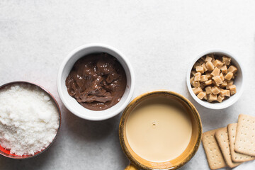 Overhead view of mise en place for making chocolate fudge with cookies and fudge pieces, Top view of ingredients of hazelnut chocolate fudge, process of making chocolate fudge