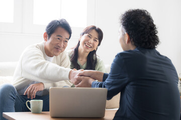 Smiling couple in their 50s receiving explanations from a salesperson Investment, insurance, real estate, etc. Wife happy with handshake and applause upon conclusion of contract.