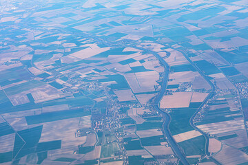 Aerial view of patchwork of green and brown fields near river