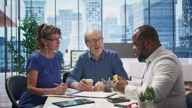 Mature couple receiving professional advice on retirement planning, exploring a new investment strategy and pension options to increase savings. Life insurance income package. Camera B.
