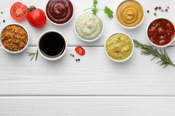 Many different sauces, spices and vegetables on white wooden table, flat lay. Space for text