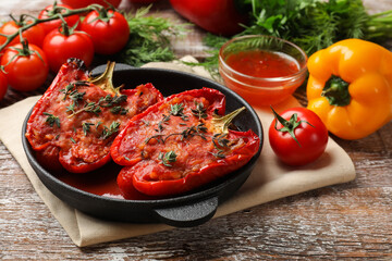 Tasty stuffed peppers in dish and ingredients on wooden table