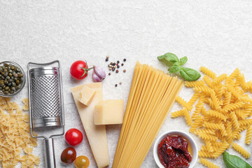 Different types of pasta, grater, spices and products on light table, flat lay. Space for text