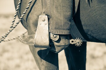 A cowboy boot with spurs, in a stirrup on a horse.