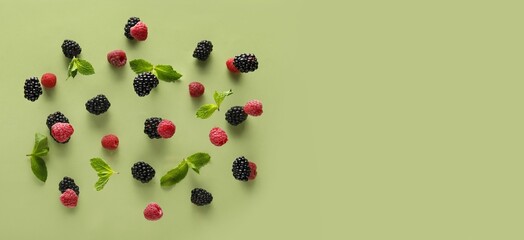 Tasty flying berries and mint leaves on green background with space for text