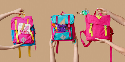 Hands with different school backpacks on beige background