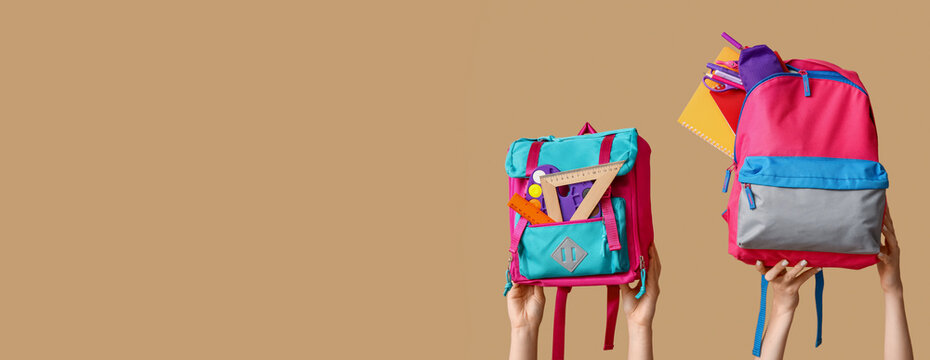Hands holding different school backpacks on beige background with space for text
