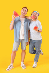Young beautiful man and woman with slices of fresh watermelon on yellow background