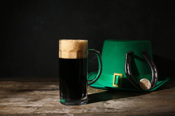 Mug of dark beer with leprechaun hat and horseshoe for St. Patrick's Day celebration on wooden...