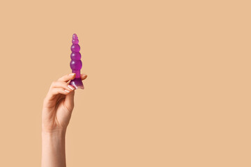 Female hand with anal plug against color background, closeup