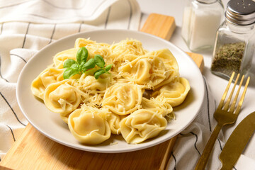 Plate of boiled dumplings with cheese and basil on white background