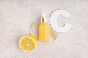 Bottle of essential oil, paper letter C and lemon on light background