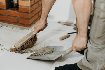 A builder man sweeps up construction debris with a broom.