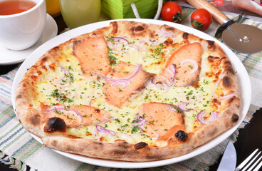 Delicious fresh salmon pizza on wooden table. 