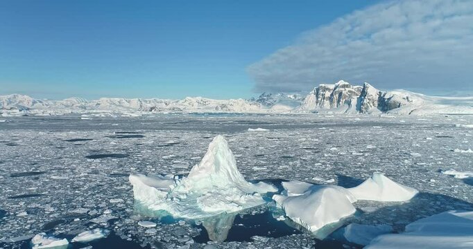 Beautiful iceberg floating arctic ocean under blue sky. Wild nature winter aerial landscape panorama. Ice floe formation drifts polar sea. Snow covered mountains in background. Ecology, climate change