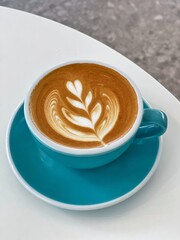 Hot latte crafted with steamed milk and espresso. Closeup Coffee latte art leave from fresh milk foam on side of marble.