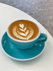 Hot latte crafted with steamed milk and espresso. Closeup Coffee latte art leave from fresh milk foam on side of marble.