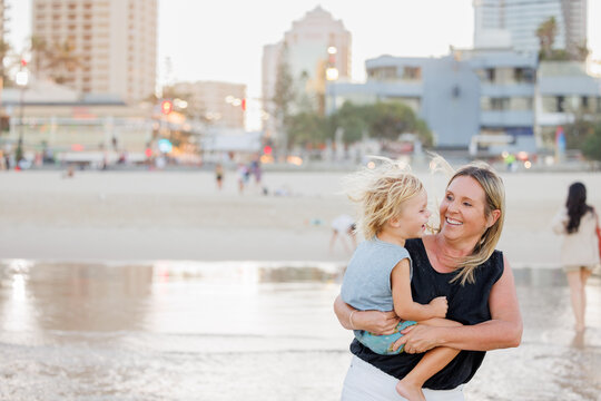 Mother holding son on the beach with Gold Coast city skyline in background