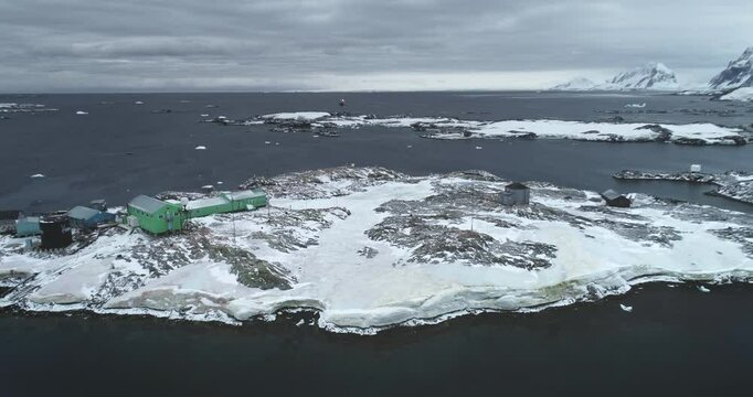 Polar research station on Antarctica coastline, Vernadsky science base. Aerial view green house buildings on rocky ocean coast. Antarctic expeditions and travel. South Pole exploration. Drone flight