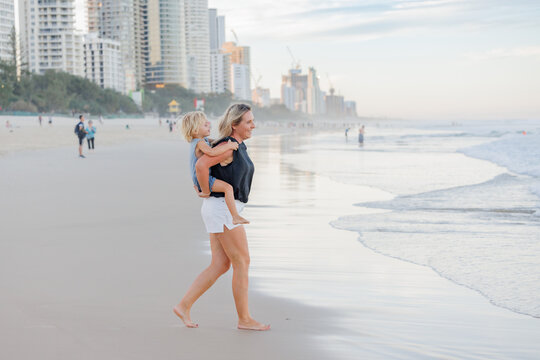 Mother giving son piggy back ride on Main Beach, Surfers Paradise on the Gold Coast