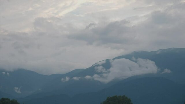 Cloudy day with trees swaying and cloud passing over mountai. n. Footage with Correct Color Profile and Basic Color Grading for Versatile Use. F-Log2, MOVH.265 All-I 4:2:2 10bit 360Mbps.