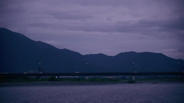 Evening bridge over river with cars and mountain backdrop. F-Log2, MOVH.265 All-I 4:2:2 10bit 360Mbps.