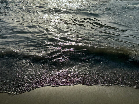 Sea waves on sand beach at summer evening