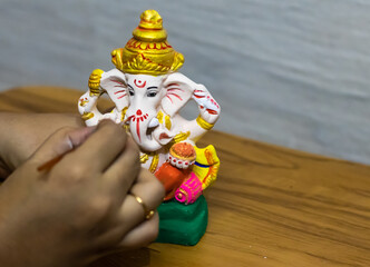 devotee coloring the hindu god ganpati idol on the occasion of ganesh chaturthi
