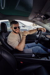 Stylish adult male with sunglasses enjoys a ride in his electric vehicle, embracing eco-friendly transportation.