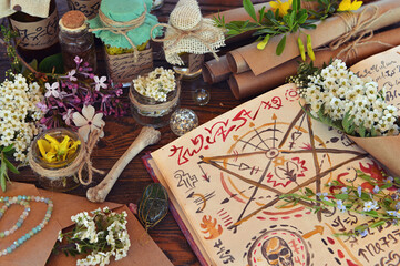Mystic still life with magic book of spells, paper scrolls and witchy ritual objects on old table....