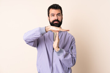 Caucasian man with beard wearing a jacket over isolated background making time out gesture