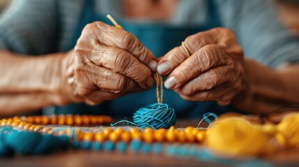 An elderly person, with hands focusing on weaving, is intertwining blue yarn with yellow beads, demonstrating intricate craftsmanship in a close-up shot. - Powered by Adobe