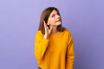 Young Slovak woman isolated on purple background listening to something by putting hand on the ear