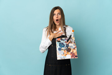 Young artist Slovak woman isolated on blue background surprised and shocked while looking right