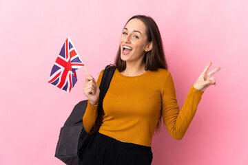 Young hispanic woman holding an United Kingdom flag smiling and showing victory sign