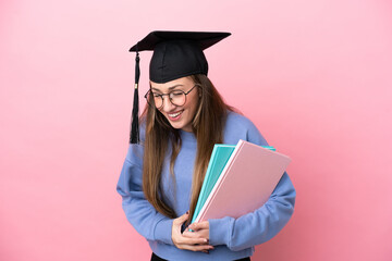 Young student woman wearing a graduate hat isolated on pink background smiling a lot