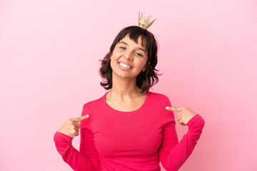 Young mixed race princess with crown isolated on pink background proud and self-satisfied