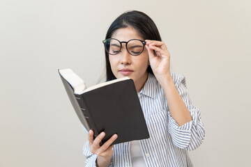 middle aged asian woman holding eyeglasses problem with vision blurred, female stare trying to read text on book at home, eye disease of old, eyesight farsightedness, health care