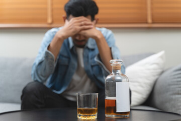 melancholy young Asian man drinks alcoholic whisky alone at home feeling dizzy after drunk
