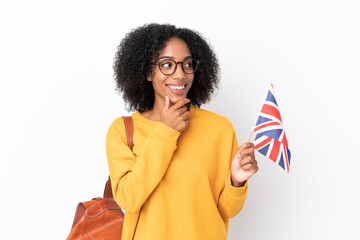 Young African American woman holding an United Kingdom flag isolated on white background looking to...