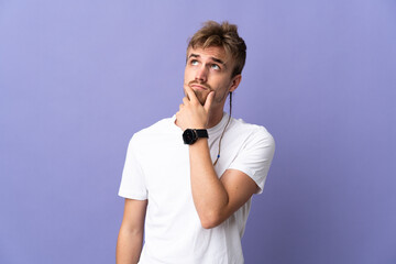 Young handsome blonde man isolated on purple background having doubts